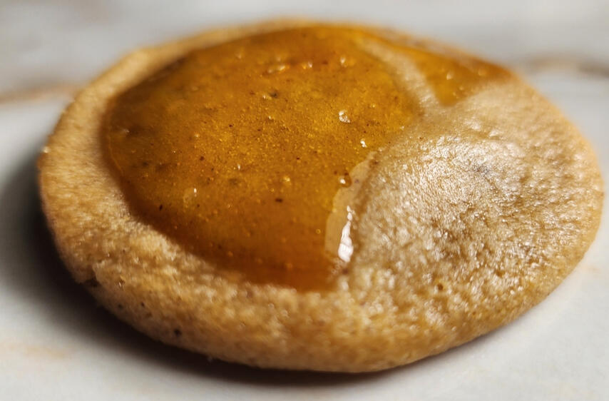 Close-up of a Honeyglass cookie with a glossy honey caramel center on a light surface.
