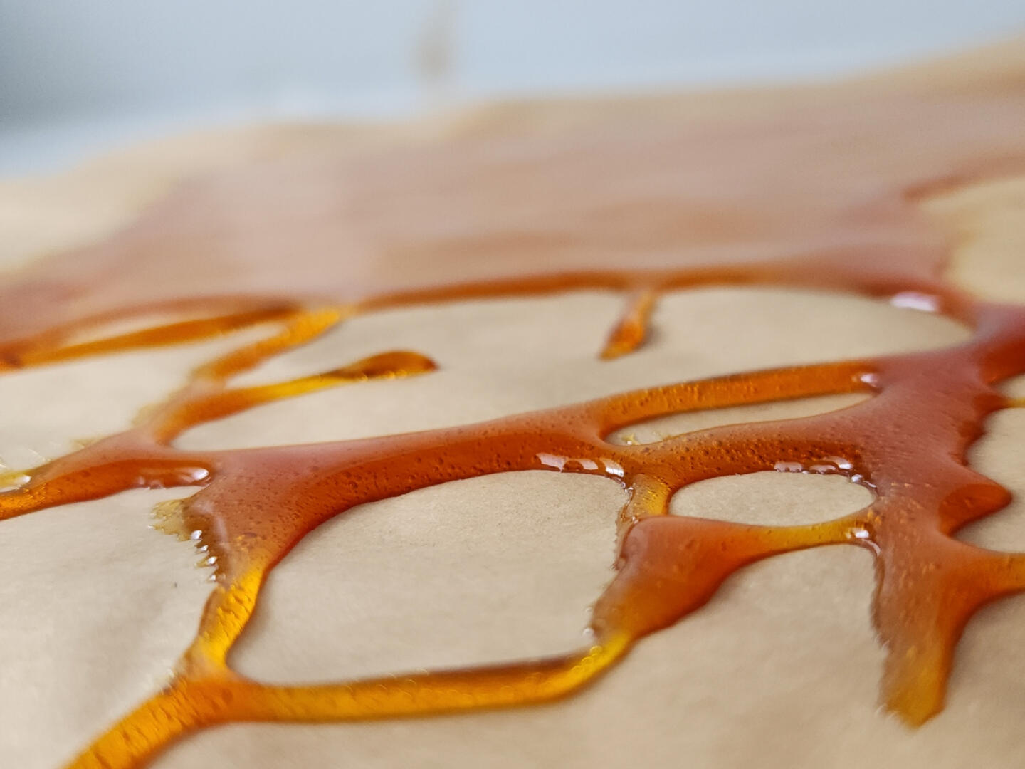 Close-up of golden honey caramel over parchment for the Honeyglass cookie.